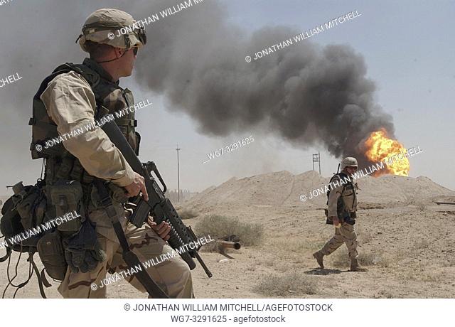 IRAQ Rumaylah Oil Fields - 02 Apr 2003 - US Army Sgt Mark Phiffer stands guard duty near a burning oil well in the Rumaylah Oil Fields in Southern Iraq
