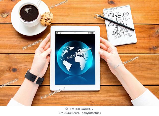 business, international, technology and people concept - close up of woman with earth globe on tablet pc computer screen, notebook and coffee on wooden table