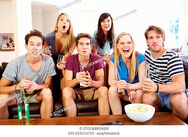 Group Of Friends Sitting On Sofa Watching Sport Together