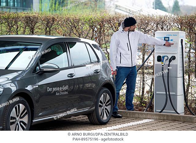 A Volkswagen employee indicates to a chargepoint in front of the VW Glaeserne manufacturing plant in Dresden, Germany, 3 April 2017