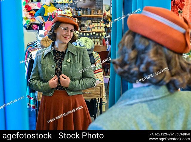 07 December 2022, Brandenburg, Werneuchen: Christin Müller, a customer at the ""Dotty&Dan"" fashion store, looks at her new clothes in a mirror