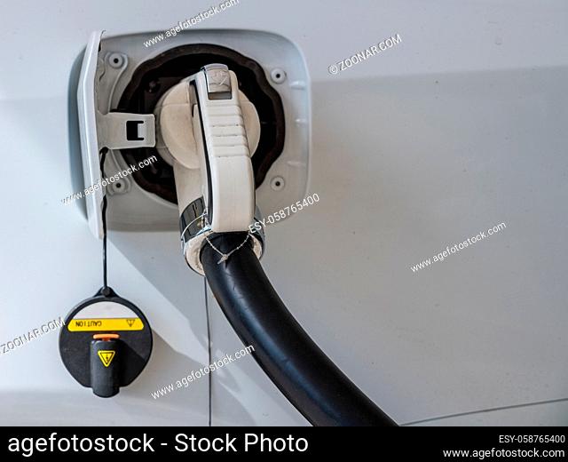 Cable plugged into car at electric vehicle charging station at motorway rest stop