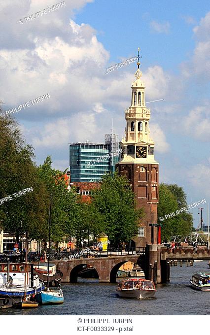 The Netherlands, North Holland, Amsterdam, canal and Montelbaanstoren tower in the background