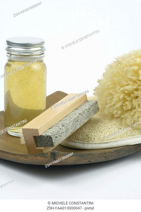 Grooming products, pumice stone, body oil, loofah and sponge on wooden tray