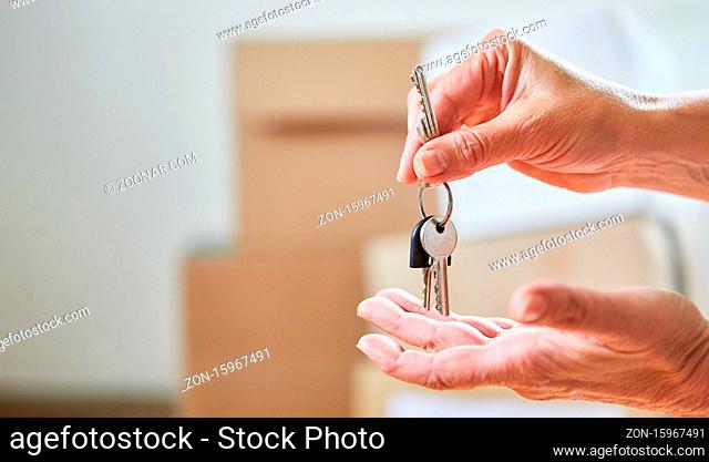Hände von Paar halten Schlüssel vom Haus nach dem Einzug ins neue Zuhause