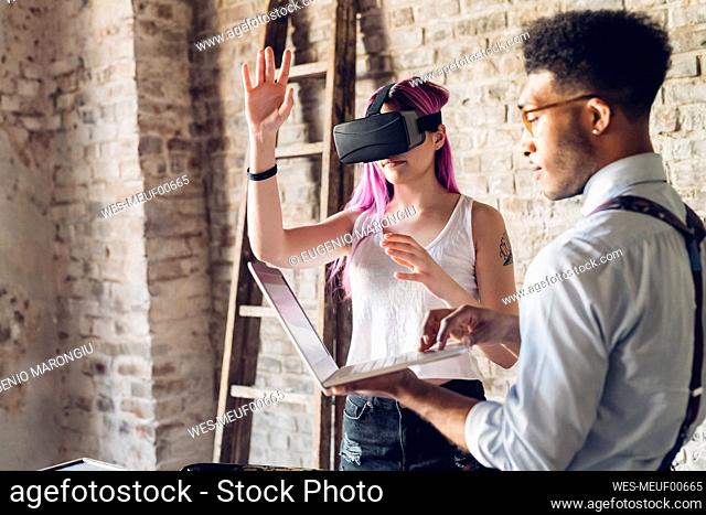 Two creative business people with VR goggles and laptop in loft office