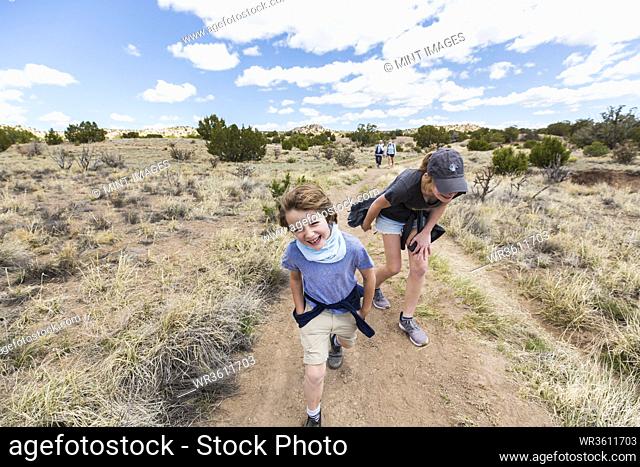 6 year old boy running on hiking trail with older sister, Galisteo Basin, NM