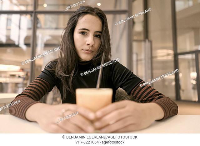 portrait of content woman with healthy juice glass enjoying break at table in café, relaxing, in Munich, Germany