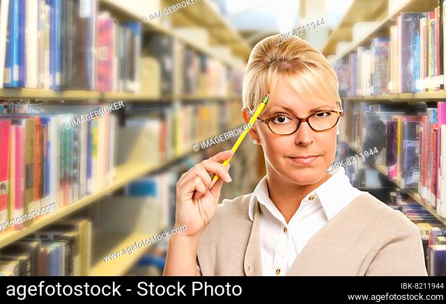 Beautiful expressive student or teacher with pencil in library