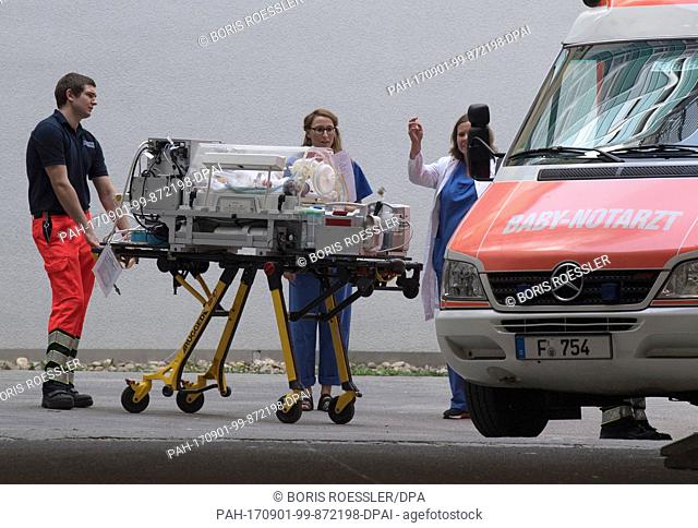 A baby is placed in an incubator which employees of the emergency service are pushing across the yard of a hospital towards an ambulance in Frankfurt am Main