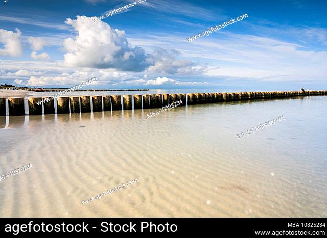 The beach on the Baltic Sea with reflection of the beautiful clouds and groynes that lead into the sea, Baltic Sea in the evening light, long exposure
