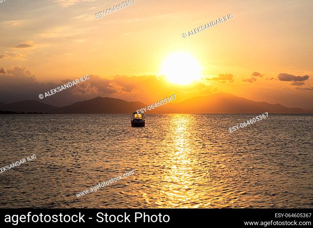 Sunset at Aegean sea at Evia island in Greece. Sun setting behind the Pelion mountain