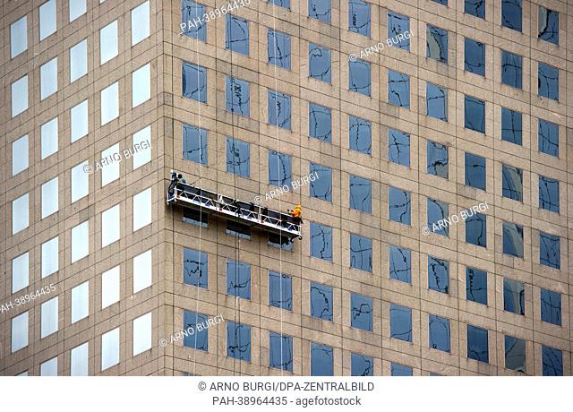 Window cleaners stand on a platform cleaning the windows of an office highrise in New York, Germany, 20 April 2013. Photo: Arno Burgi | usage worldwide