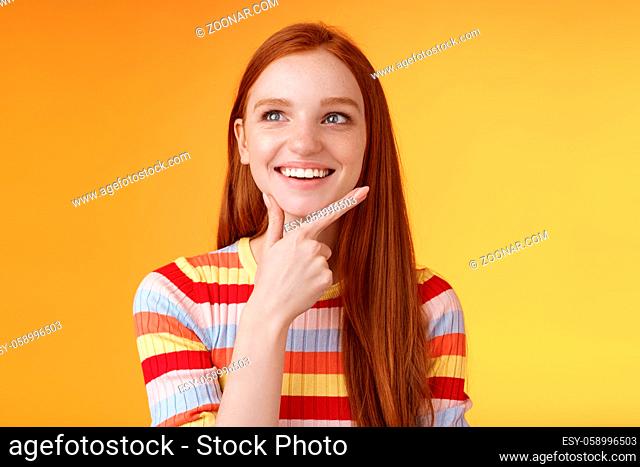 Creative satisfied smart redhead girl got excellent idea touching chin smiling broadly delighted good thought look upper left corner thinking pondering made up...