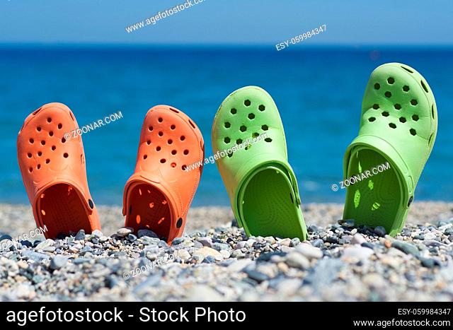 Green and orange sandals on a cobblestones beach