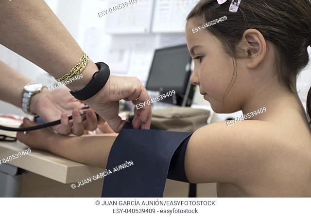 Little girl being giving blood pressure test doctor. Periodical pediatric review concept