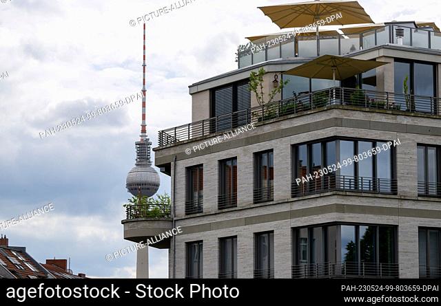 PRODUCTION - 19 May 2023, Berlin: The TV tower rises into the sky against the backdrop of a luxury new building in Berlin's Prenzlauer Berg district
