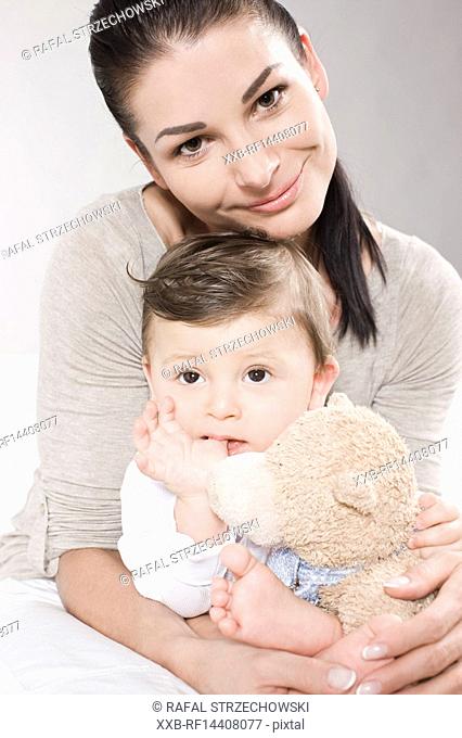 Mother hugging baby with teddy bear