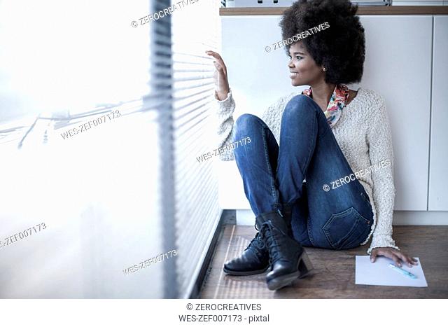 Woman sitting on the floor in office looking out of window