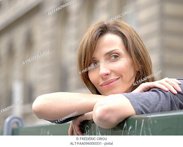 Woman leaning against railing, looking away in thought, portrait