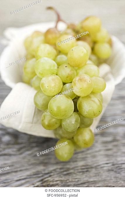 Green grapes on cloth in white bowl