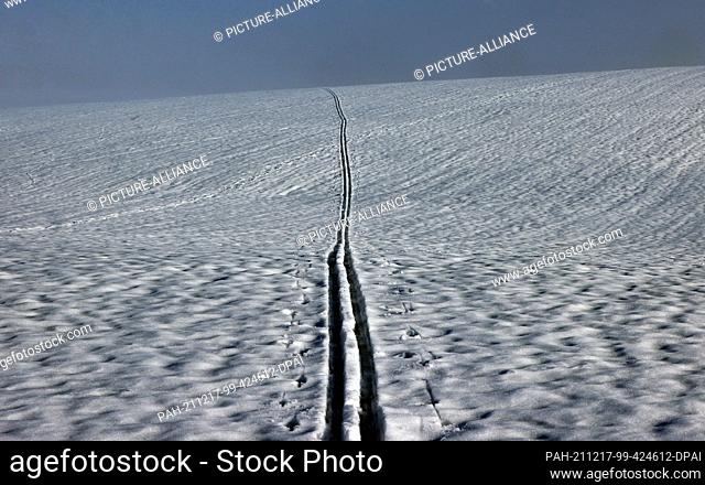 17 December 2021, Bavaria, Ruderatshofen: The tracks of a cross-country skier stretch across the snow-covered landscape. Photo: Karl-Josef Hildenbrand/dpa