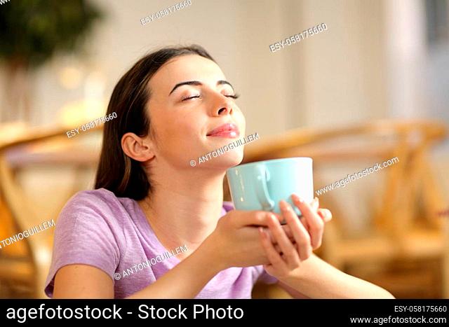 Happy woman smelling coffee breathing fresh air at home