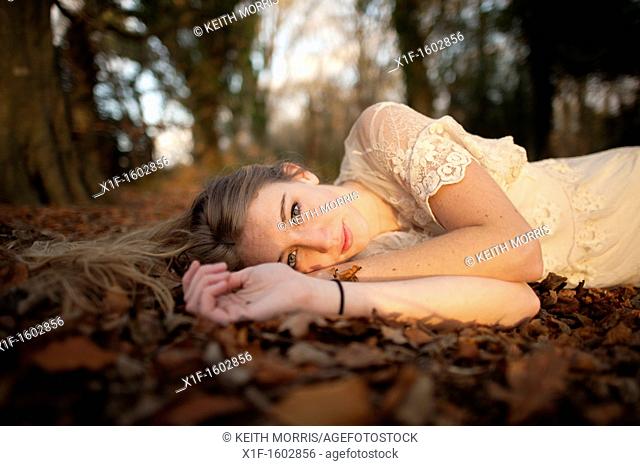 a slim blonde woman girl alone in woodland autumn afternoon daytime UK