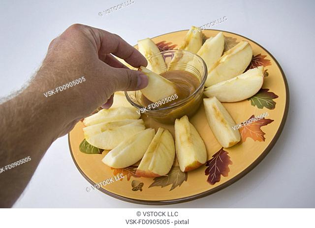 Man dipping apple in caramel dip
