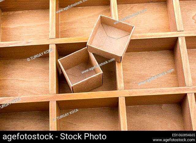 Open cardboard box inside a wooden box with compartments