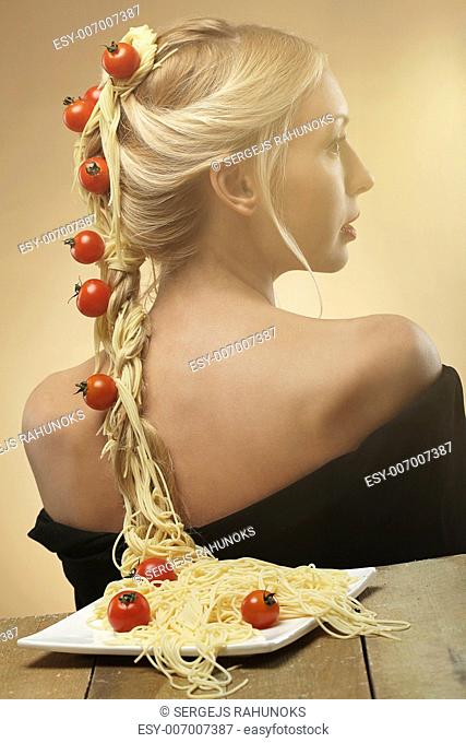 Art photo of young beautiful woman with pasta and tomatoes in her hair