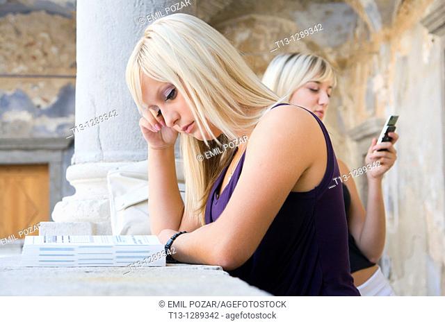 One girl is studying another is talking on the cellular phone