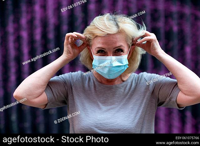 Elderly woman in face mask put on outdoor. Old aged female wearing protective medical mask