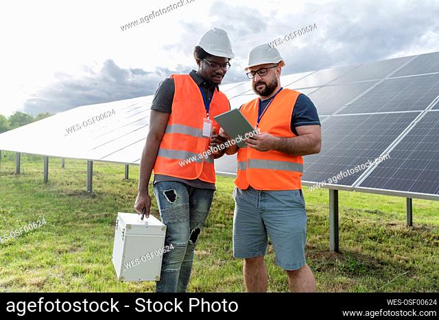 Multiracial engineers discussing over tablet PC at solar station