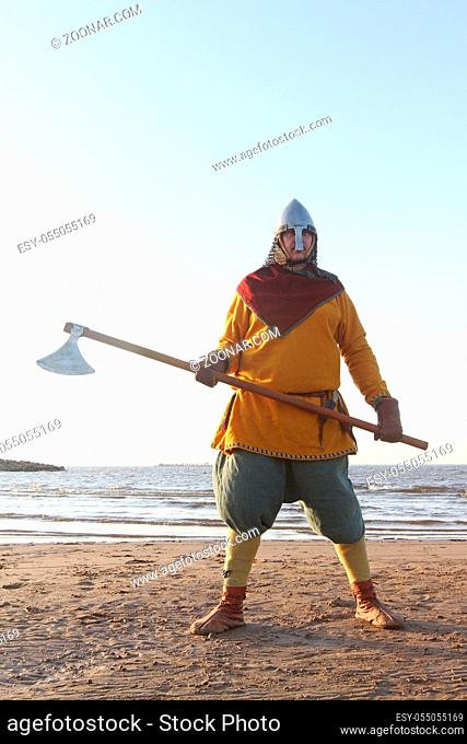 Portrait of slavic warrior reenactor with axe posing outdoors at seaside