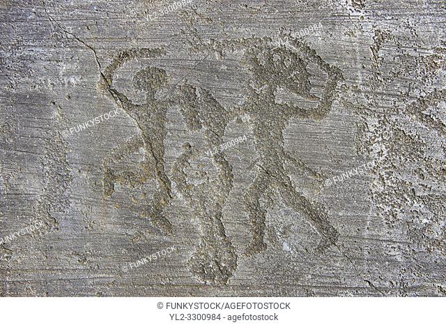 Petroglyph, rock carving, of two warriors fighting, the one on the right has a headress and they both have shields. Carved by the ancient Camunni people in the...