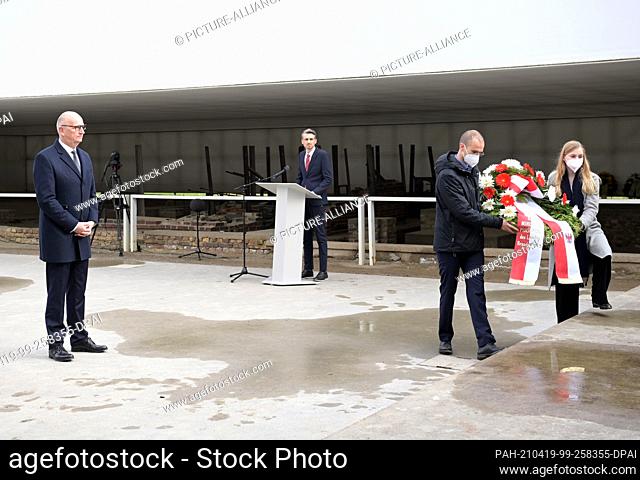 18 April 2021, Brandenburg, Oranienburg: Dietmar Woidke (l, SPD), Minister-President of Brandenburg, stands near the sculpture where helpers lay a wreath from...