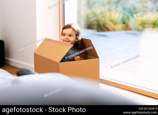 little baby girl sitting in cardboard box at home