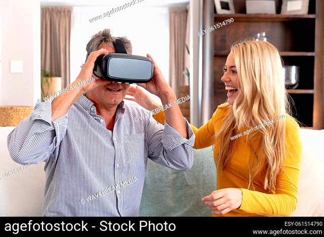 Senior Caucasian man and his adult daughter using a VR headset at home