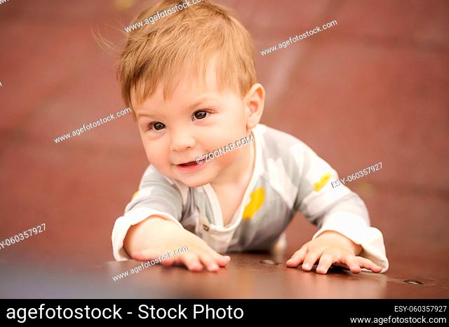 Concept: family values. Portrait of adorable innocent funny brown-eyed baby playing at outdoor playground