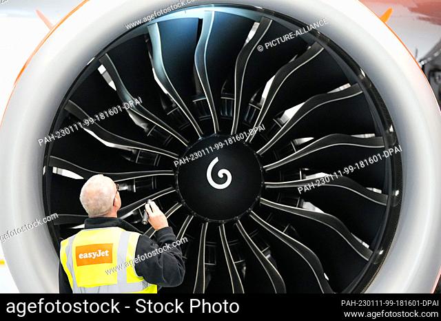 11 January 2023, Brandenburg, Schönefeld: Olaf Groß, Licence Engineer at easyJet, checks the engine of an Airbus A320 Neo with a flashlight before the start of...