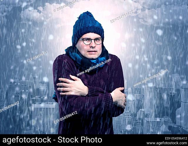 Young man freezing in warm clothing with city concept
