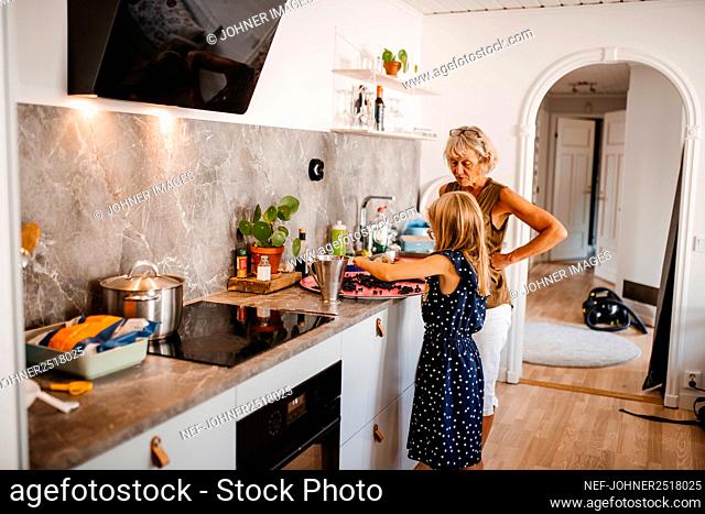 Grandmother with granddaughter preparing food in kitchen