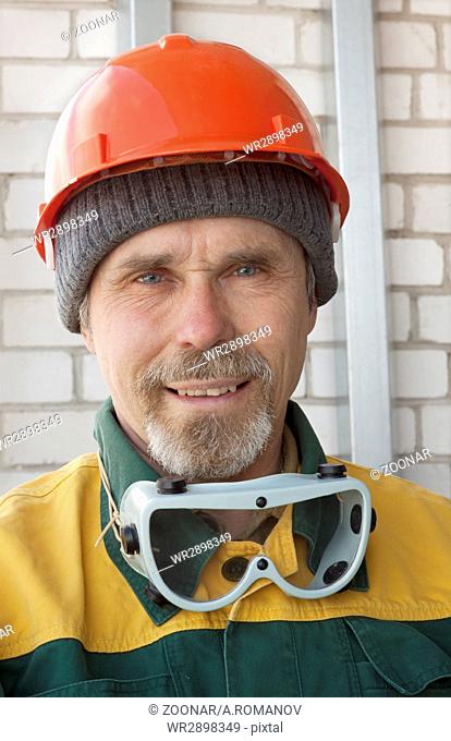 An elderly worker in protective helmet