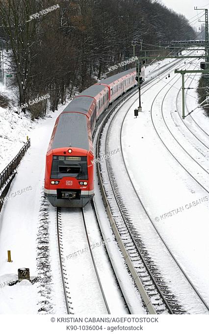S-Bahn - local red train of the public transportation services of Deutsche Bahn in Hamburg with snow on the tracks, Northern Germany, Europe
