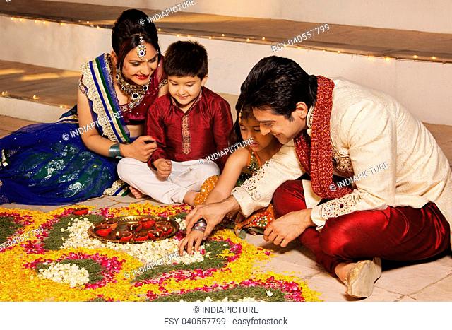Family arranging diyas on rangoli