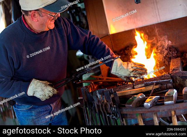 A blacksmith working at an old iron forge
