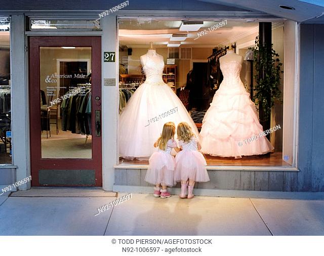 2 girls standing at window looking at gowns dreaming about a dance