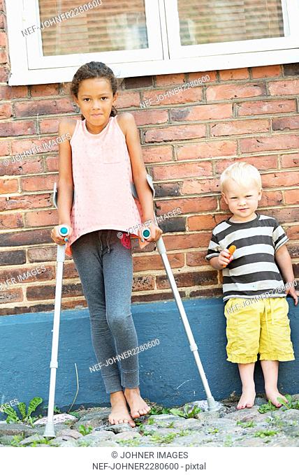 Girl with crutches and boy looking at camera