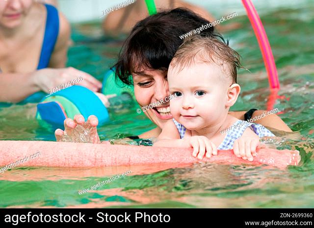 happy smiling little girl with mother swimming at water pool